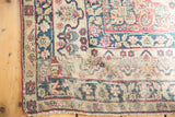 Antique Kerman rug corner: distressed traditional floral patterns in cochineal red and navy.