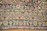 Antique Kerman rug's Safavid-inspired main border with cochineal red, navy, and aged texture.