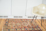Distressed antique Caucasian rug with geometric tribal patterns and muted earth tones.