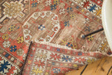 Distressed geometric tribal motifs and tattered fringe on an antique Caucasian rug.