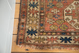 Distressed fringe and tribal geometric motifs on an antique Caucasian rug corner.