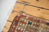 Distressed corner of a circa 1910 Caucasian rug, highlighting tattered ends and geometric motifs.