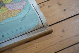 Close-up of antique British Isles map's bottom, revealing wooden dowel and prominent discoloration.
