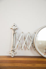 Aged silver extended accordion arm and round frame of the antique barber mirror.
