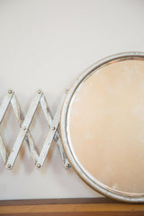Aged silver paint on the antique barber mirror's round frame and accordion arm.
