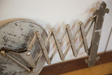 Antique barber mirror's aged silver accordion mechanism and fleur de lis hardware.