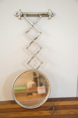 Circular antique barber mirror, showing its aged silver paint and reflection.