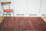 Distressed Lilihan rug featuring deep burgundy field, navy border, and Sarouk style floral tendrils.