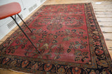 Distressed Lilihan rug featuring a faded burgundy field with Sarouk-style vines and dark navy border palmettes.