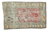 Distressed Antique Prayer Caucasian rug, red Mehrab, ivory, orange, and charcoal geometric patterns.