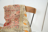 Antique Caucasian prayer rug, distressed texture with geometric red and ivory patterns.