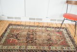 Demirci rug corner, highlighting its worn field, detailed geometric borders, and muted coral and blue.