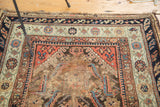 Antique Demirci rug corner with intricate dark blue, coral borders and worn pile.