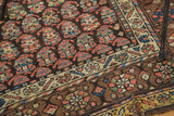 Antique Kurdish rug's saturated rainbow boteh motifs on a dark ground with geometric borders.