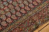 Intricate hand-knotted boteh motifs, vibrant geometric border, and short fringe of the antique Kurdish rug.