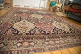 A full-length angled view of the antique Lavar Kerman carpet's repeating multi-paneled floral design.