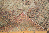 Antique Lavar Kerman rug corner folded, revealing distressed floral pattern and cyprus tree border.