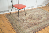 Distressed antique Lavar Kerman rug with faded mil fleur medallion and scrolling vine border.