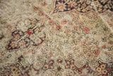 Exposed foundation showing intricate faded floral mil fleur motifs on this antique Kerman rug.
