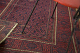 Belouch rug corner, geometric floral patterns on navy ground, brick red borders.