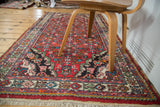 Vintage Borchalou rug's dark spandrel with herati pattern, multi-color border, and cream fringe.