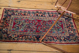 Traditional Sarouk rug with cherry red field, navy border, and intricate floral motifs.
