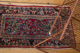 Vintage Sarouk rug fragment with rich cherry red, navy blue, and gem-tone floral patterns.