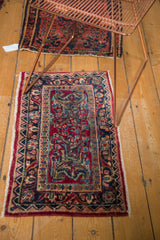 Vintage Sarouk rug corner showing cherry red field and navy blue floral border.