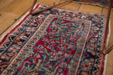 Vintage Sarouk rug detail showing intricate floral leaves, cherry red field, and gem tones.