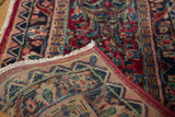 Vintage Sarouk fragment corner folded to show red seaming, fringe, and detailed floral patterns.