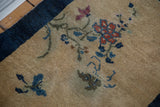 Antique Peking rug's beige gold field detail with purple butterfly, red blossom, and indigo border.