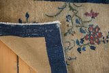 Antique Peking rug corner turned, revealing secured indigo border and beige gold field.