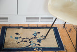 Beige field of an antique Peking rug with blue floral and butterfly motifs, dark indigo border.