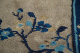 Close-up of antique Peking rug's beige field, blue blossoming tendrils, and cobalt border.
