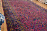 Distressed traditional Persian Meshed rug with burgundy plum field, scrolling palmettes, and blue-gold border.