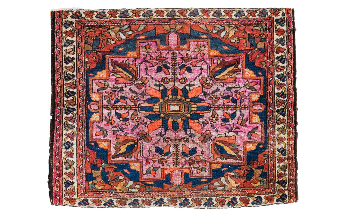 Antique Lilihan square mat with softened raspberry, bold tangerine, deep blue floral motifs.