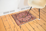 Angled view of antique Lilihan rug's softened raspberry field with nuanced blue and tangerine patterns.
