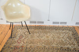 Antique Caucasian rug with distressed geometric patterns and stylized motifs in earthy tones.