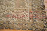 Geometric borders with patterned rhythm and time-softened hues on a distressed Caucasian rug.