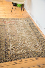 Geometric ram's horn motifs and patterned borders on a distressed antique Caucasian rug corner.