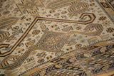 Distressed antique Caucasian rug corner with geometric ram's horn motifs and patterned borders.