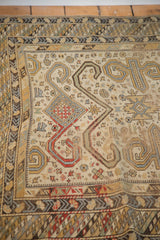 Distressed texture with geometric Perpedil motifs and rhythmic borders on antique Caucasian rug.