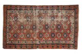 Antique distressed Caucasian rug features brick red field, splayed floral motifs, Lotto border. 3'5