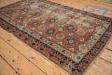 Distressed antique Caucasian rug corner, featuring brick red splayed floral field and Lotto border.