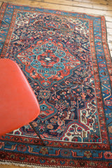 Bottom corner of vintage Dargazine rug, showing fringe, brick red and aqua curvilinear motifs.