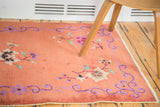 Vintage Art Deco rug edge, blush peach field with violet and mint green floral branches.