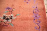Art Deco rug close-up: blush peach field, violet flowers, mint green branches.