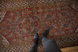 Antique Northwest Persian rug's distressed brick red field, indigo blues, and saffron patterns underfoot.