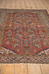 Antique Northwest Persian rug end: distressed brick red field, indigo border, and fringe.