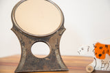 Chippy paint and distressed metal on the vintage Hollywood mirror's Art Deco stand.